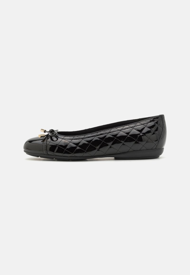 Ballerine plate en cuir verni noir avec motif matelassé et petit nœud avec embouts métalliques dorés sur le bout, semelle plate.