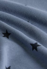 Blauwe stof met een zachte textuur, voorzien van zwarte sterpatronen, met subtiele plooien en een glad oppervlak.