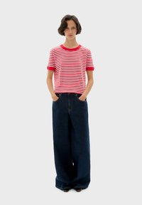 Rood en wit gestreepte t-shirt met korte mouwen, gecombineerd met brede, donkere denim jeans met een comfortabele pasvorm en zijzakken.