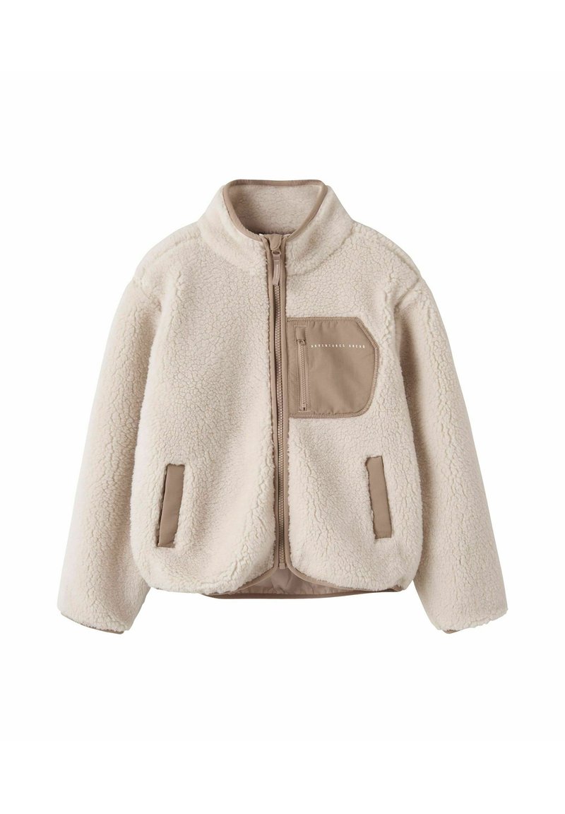 Veste en polaire couleur crème avec un col haut, fermeture éclair à l'avant, deux poches latérales et une poche en tissu beige sur la poitrine, présentant une surface texturée.