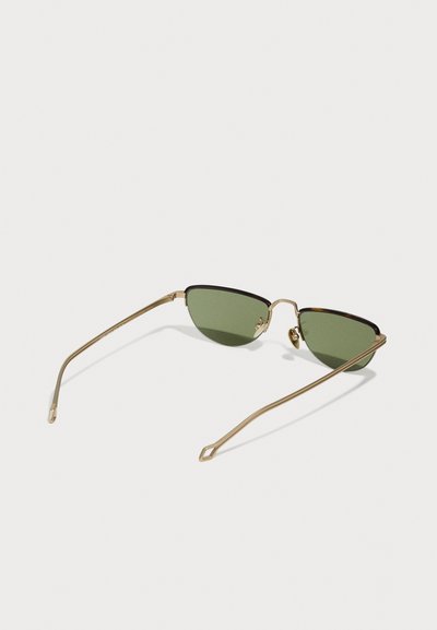 Gold metal sunglasses with olive green lenses, cat-eye shape, slim arms, and unique angled detailing on the tips.