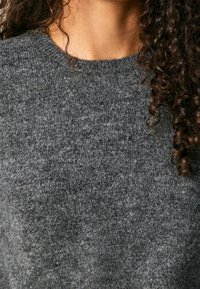 Gray knitted sweater with a round neckline. The texture appears soft and dense, featuring a subtle variation in shades of gray.