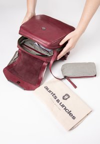Burgunderfarbene Ledertasche mit glatter Oberfläche, Reißverschluss und strukturiertem Innenraum. Inklusive einem grau gestreiften Beutel und einem Canvas-Staubbeutel.