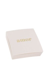 Scatola di gioielli bianca con lettering dorato "amor" centrato sul coperchio, sfondo semplice.