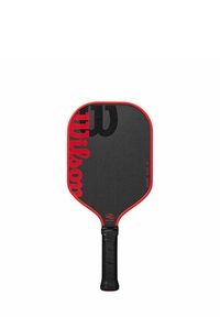 Paddle da pickleball con una superficie rettangolare nera, bordo rosso e manico di gomma nera testurizzata. Presenta un grande logo "Wilson" nero.