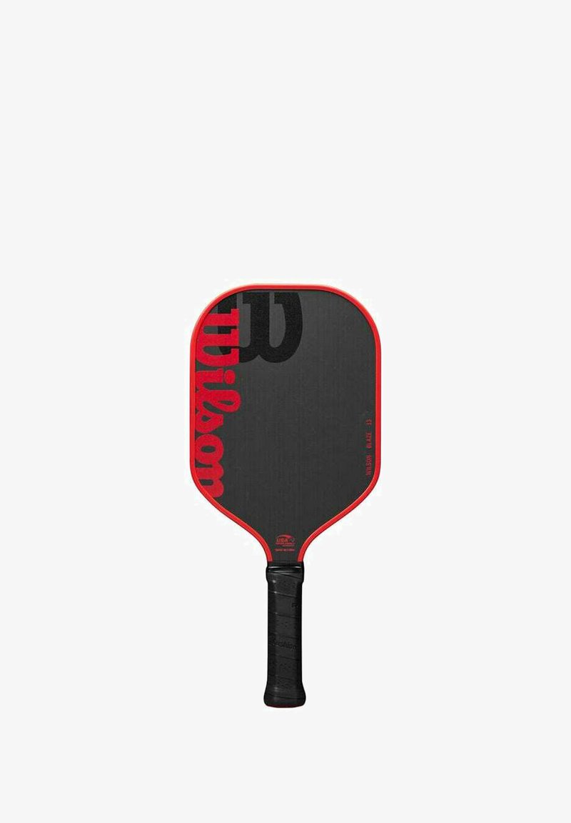 Paddle da pickleball con una superficie rettangolare nera, bordo rosso e manico di gomma nera testurizzata. Presenta un grande logo "Wilson" nero.