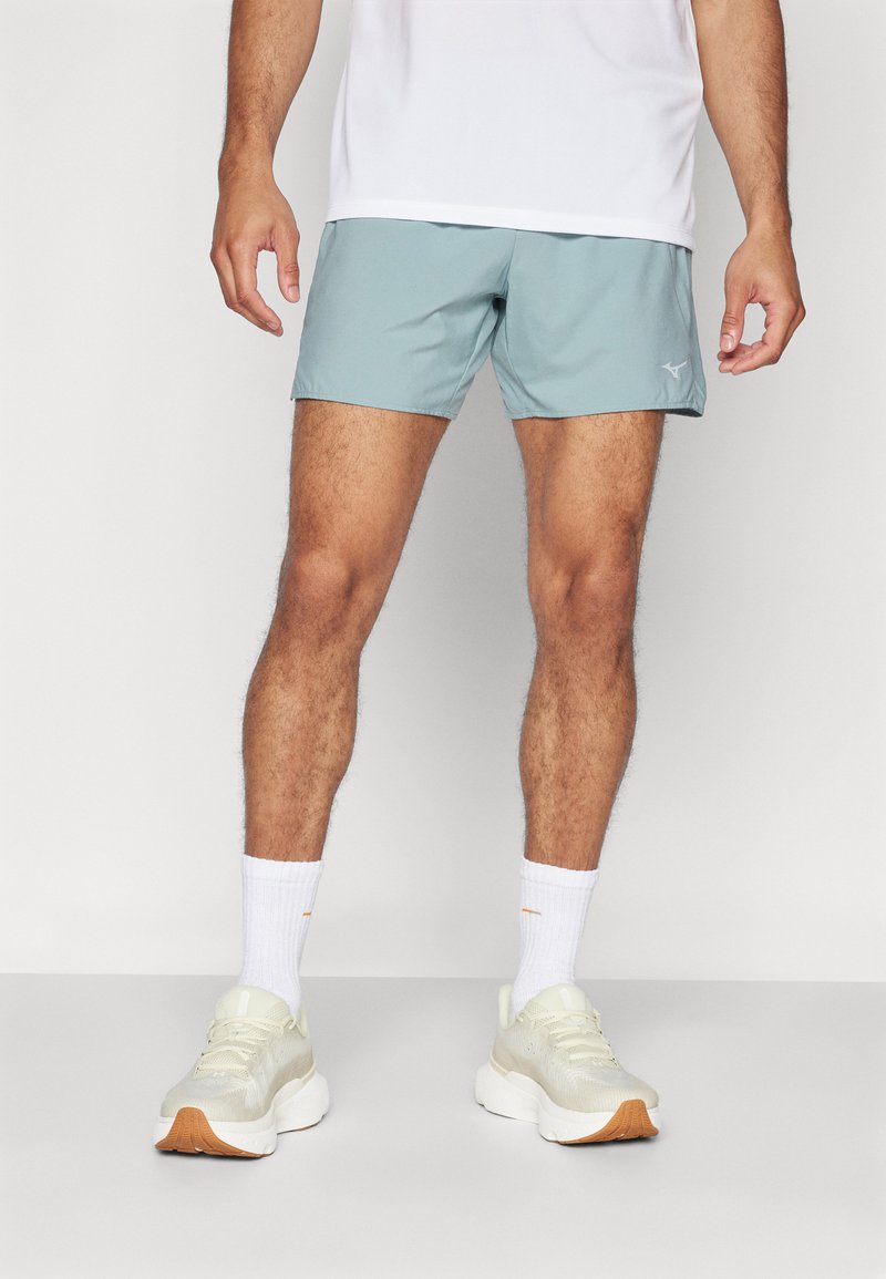 Pantalones cortos deportivos de color azul claro, hechos de una tela transpirable, con una textura suave y una cintura elástica. Se llevan con calcetas blancas y zapatillas de color claro.