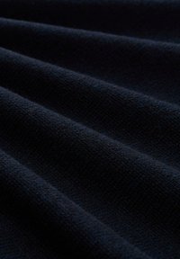 Donker marineblauw stof met een zachte, gestructureerde oppervlakte en een subtiel geribbeld patroon, met zachte plooien en een rijke, diepe kleur.