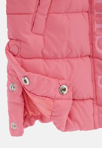 Giacca a vento rosa con texture trapuntata, dotata di bottoni a pressione, un morbido rivestimento interno e una discreta stampa del logo all'esterno.