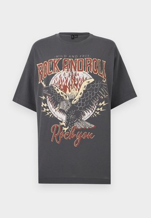 Σκούρο γκρι T-shirt με φλόγινο κύκλο, γραφικό ιπτάμενου αετού και κείμενο «Wild and Free Rock and Roll Rock you» σε vintage στυλ.