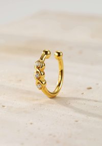 Goldring mit einem glatten, abgerundeten Design, das drei klare Edelsteine in einer Kurve enthält und somit die moderne Ästhetik unterstreicht.