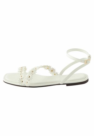 Weiße flache Sandalen mit floralen Verzierungen und goldfarbener Hardware. Sie verfügen über eine glatte Textur und einen einzelnen verstellbaren Knöchelriemen.