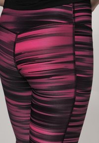 Leggings atletici aderenti in un motivo a strisce astratte rosa e nere. Realizzati in un tessuto elasticizzato e liscio con cuciture piatte per garantire comfort.