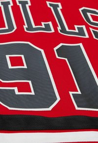 Rotes Trikot mit schwarzen und weißen Akzenten, versehen mit großen grauen Zahlen "91" und dem Text "BULLS", aus strukturiertem Stoff.