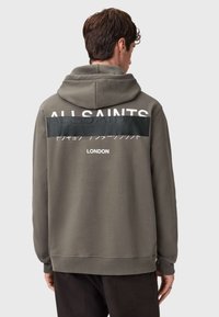 Bluza z kapturem w kolorze khaki z dużym białym logo "ALLSAINTS" i czarnym poziomym panelem. Posiada kaptur ze sznurkiem i ściągacze przy mankietach.