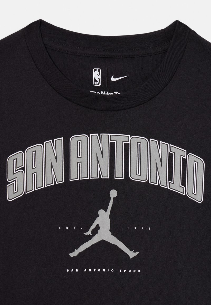 T-shirt en coton noir avec "SAN ANTONIO" imprimé en gras gris, accompagné d'une silhouette de basket-ball et de "EST 1973" en dessous. Logo Nike inclus.