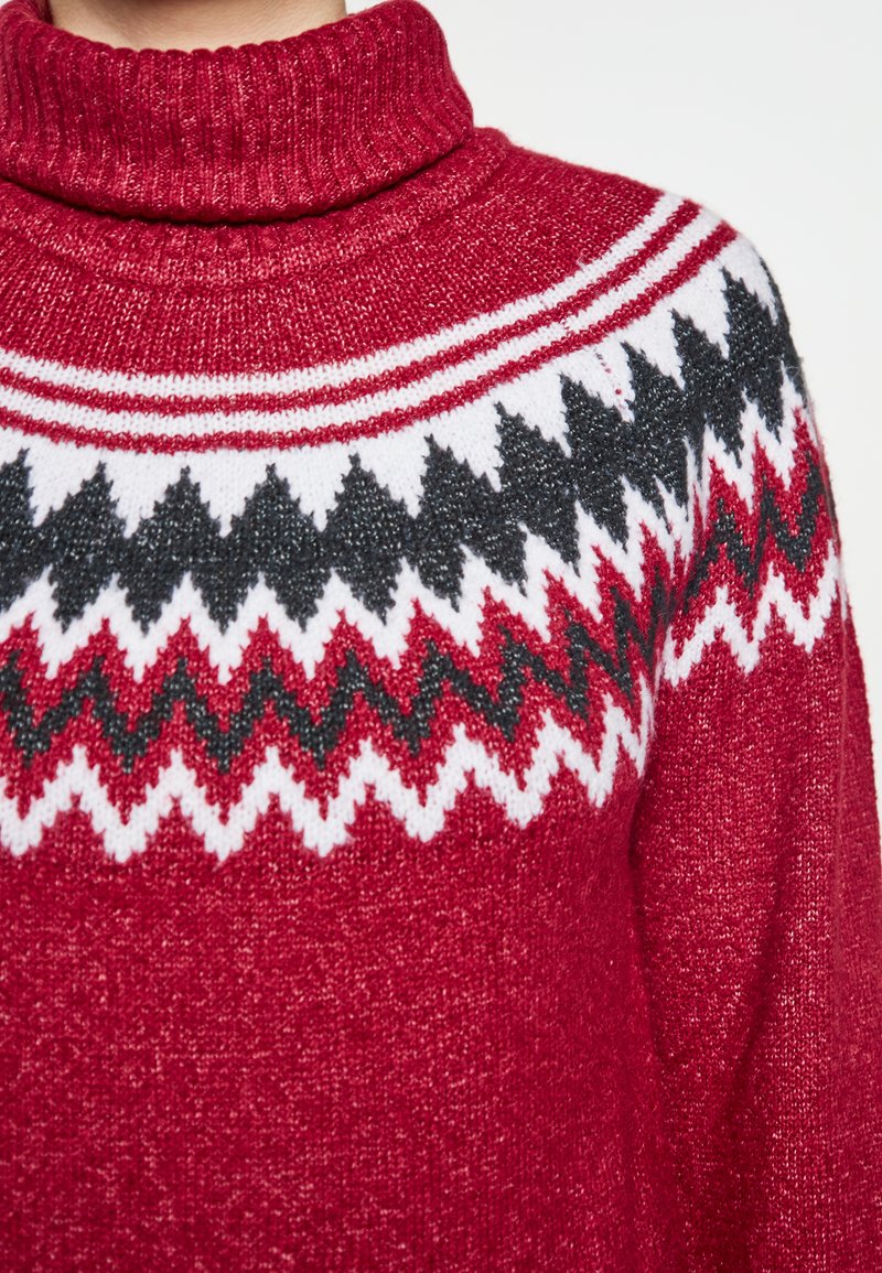 Roter gestrickter Pullover mit hohem Kragen, Zickzackmustern in Rot, Weiß und Schwarz auf der Brust. Weiche Textur mit Rippakzenten.