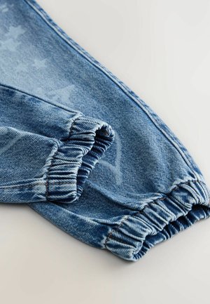 Pantaloni din denim cu mansete elastice, într-o nuanță de albastru deschis. Prezintă modele subtile cu stele și cusături în contrast pe linii.
