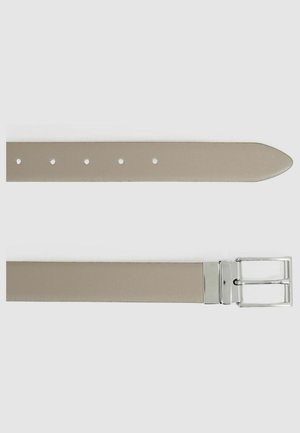 Cinturón sintético beige con textura suave. Presenta una hebilla de metal en tono plateado y agujeros espaciados uniformemente a lo largo de la longitud para ajustes.