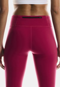 Kohandatud roosad retuusid, millel on sile tekstuur, kõrge vöökoht ja lukkude tasku taga. Õmbluste detailid on nähtavad külgedel.