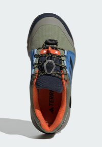 Buty trekkingowe z zieloną syntetyczną cholewką, niebieskimi akcentami i czarnym siateczkowym językiem. Wyposażone w szybki system sznurowania oraz pomarańczową podszewkę.