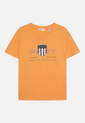 Oranges Baumwoll-T-Shirt mit rundem Halsausschnitt, kurzen Ärmeln und einem grafischen Logo mit Streifen sowie der Jahreszahl "1949" in der Mitte.