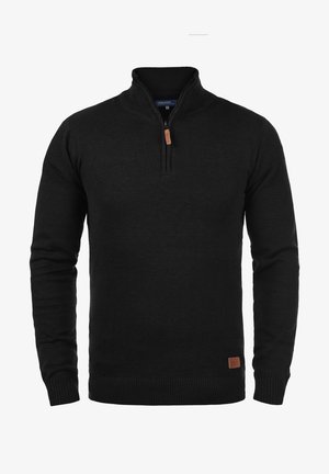 Črna pletena pulover z ovratnikom na pol-zadrgo, rebrastimi manšetami in robom. Ima rjavo usnjeno oznako na spodnjem levem delu.