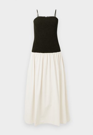 Maxi obleka z oprijetim črnim gubanjem v zgornjem delu, tankimi naramnicami in razkošnim belim spodnjim delom z teksturiranim vzorcem.