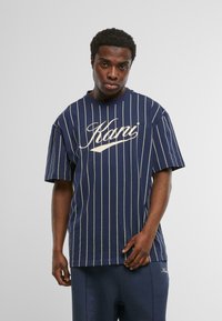 Jūras spēku svītrains T-krekls, izgatavots no kokvilnas, ar īsām piedurknēm, apaļu kakla izgriezumu un krēmkrāsas logo druku priekšpusē. Brīva piegriezte.