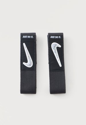 Два черни каиша за китка с бели петнисти лога на Nike swoosh и текст "JUST DO IT." на обикновен светъл фон.