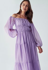 Laventelin off-the-shoulder mekko, jossa on puffattu pitkät hihat, smockattu vyötärö ja kerroksellinen hameosa, valmistettu kevyestä, teksturoidusta kankaasta.