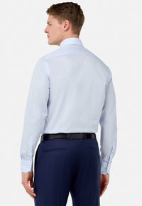 Lichtblauw gestreept overhemd met lange mouwen, knoopmanchetten en een kraag, in combinatie met donker marineblauwe broek en een zwarte riem.