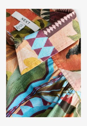 Skjorta med krage med livliga blommönster och geometriska mönster i rosa, blått, grönt och orange. Tillverkad av lätt texturerat tyg. Varummärkets etikett synlig.