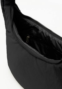 Schwarze Nylon-Schultertasche mit einem Reißverschluss, ausgestattet mit einem strukturierten Rand und einem Innenreißverschlussfach für sichere Aufbewahrung.