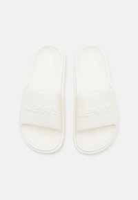 White slide sandals made of smooth rubber, featuring a wide strap embossed with "Levi's" text and textured footbed for grip.