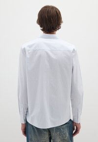 Camicia a maniche lunghe bianca con strisce verticali blu, dotata di colletto classico e polsini con bottoni, realizzata in tessuto leggero.