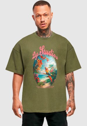 Grøn oversized t-shirt med et farverigt papegøje- og blomstermotiv inden for en oval ramme. Teksten "2y Studios" er placeret over grafikken.
