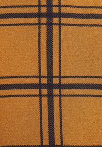 Tissu jaune moutarde avec un motif à carreaux noir comportant des lignes verticales et horizontales épaisses et fines qui se croisent.