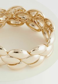 Bracelet en chaîne dorée composé de segments ovales liés, avec une finition métallique polie, présentant une texture lisse et brillante.