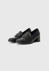 Black leather loafers with a low block heel, featuring a strap across the instep and decorative stitching along the edges. Smooth texture.