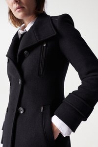Manteau en laine noir avec un col cranté, boutons double boutonnage, poche zippée et silouhette cintrée, doté d'un tissu texturé.