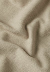 Beige tyg med en mjuk, texturerad väv som visar subtila åsar och en slät fall. Materialet verkar lätt och mångsidigt.