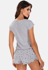 Grijze katoenen pyjama set bestaande uit een T-shirt met korte mouwen en een korte broek met ruches. De shorts hebben hartpatronen in verschillende texturen.