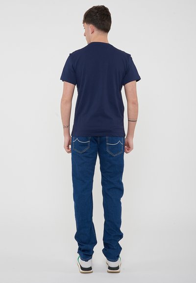 Maglietta a maniche corte blu navy con vestibilità regolare, abbinata a jeans blu scuro con due tasche posteriori e dettagli di cucitura bianca.