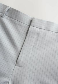 Grå stofbukser med en fin lodret næstebåndmønster, flad front og en diskret baglomme. Glat tekstur og skræddersyet design.