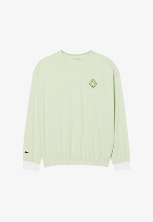 Camicia verde chiaro a maniche lunghe con righe verticali, polsini a coste, vita elasticizzata e logo a rombo nero e giallo sul petto.