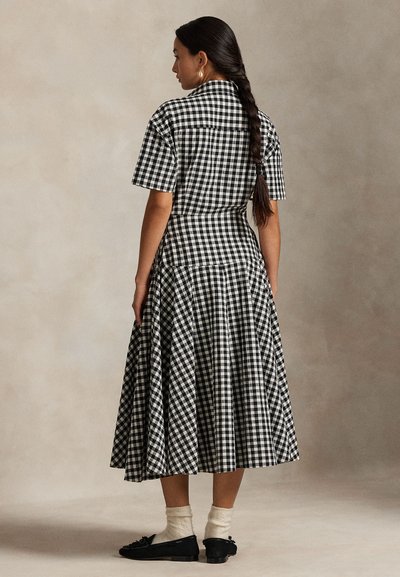 Juoda ir balta languota suknelė trumpomis rankovėmis, aptemptu liemeniu ir platėjančia suknelės dalimi. Suknelė turi užsegamą apykaklę ir siūlės detalę gale.