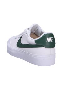 Zapatilla blanca con un upper de cuero liso, acento de suede verde en el talón y el logo swoosh, suela de goma texturizada y cuello acolchado.