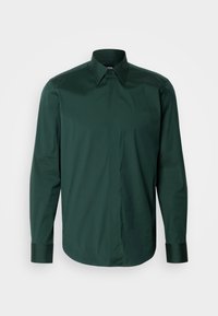 Camisa de botones de manga larga verde oscura, hecha de algodón suave, con cuello y puños puntiagudos, de corte recto y con un minimalismo en el diseño.