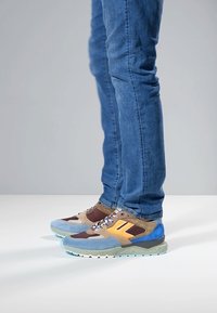 Scarpe sportive multicolori con una combinazione di tonalità blu, marrone e arancione, caratterizzate da una tomaia testurizzata, suole spesse e lacci decorati.